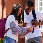 One female student showing a male student something on her phone.
