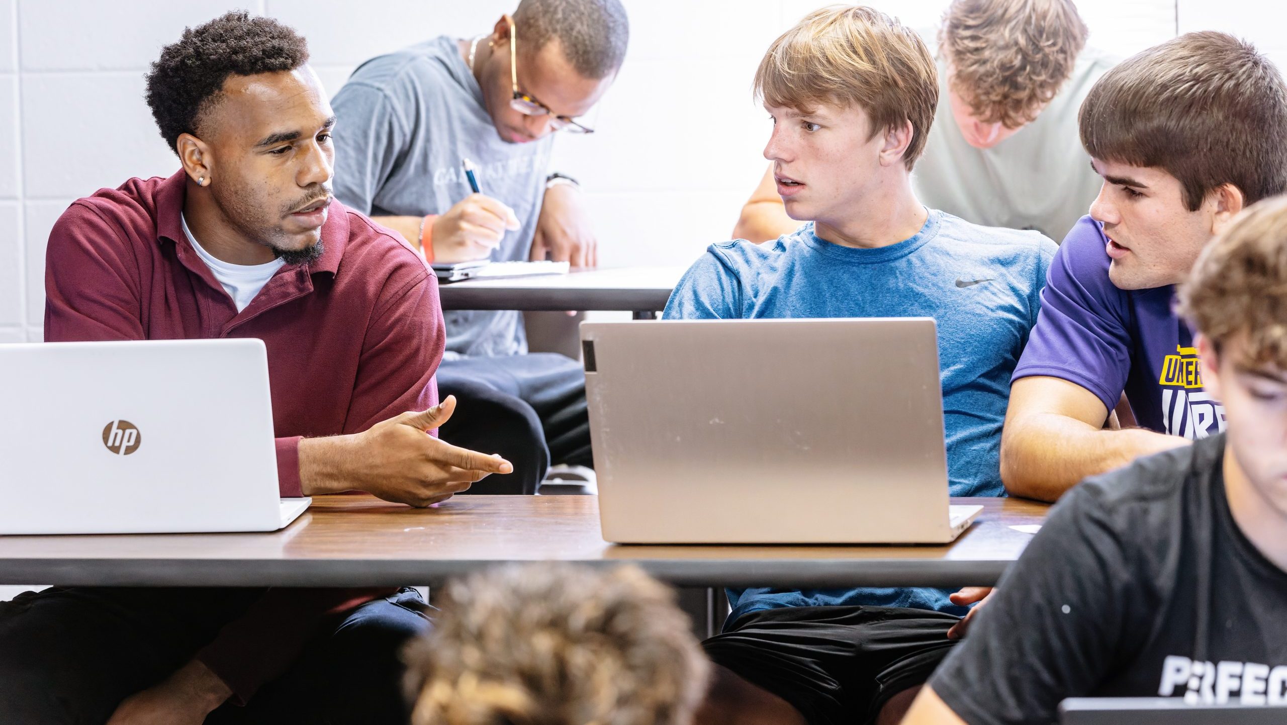 Students on their laptops discuss problems.