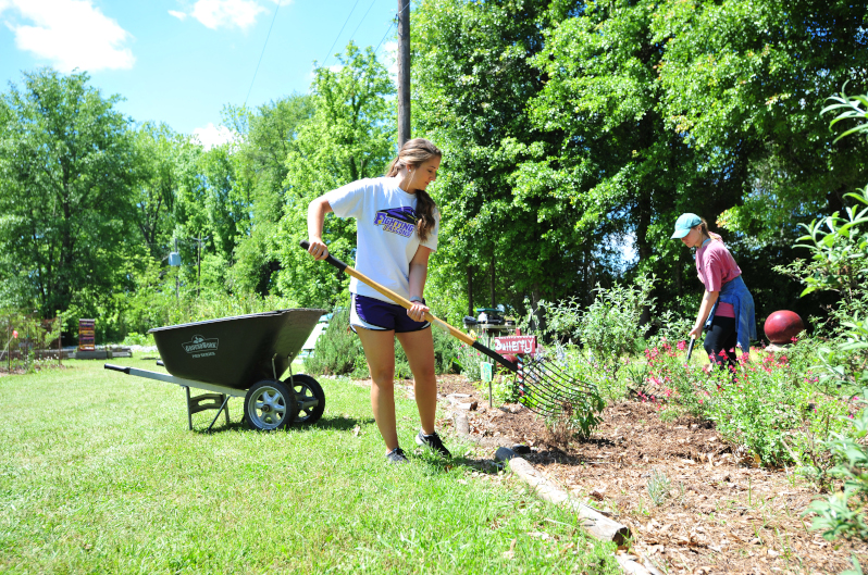 Female student shoveling at the Community Garden