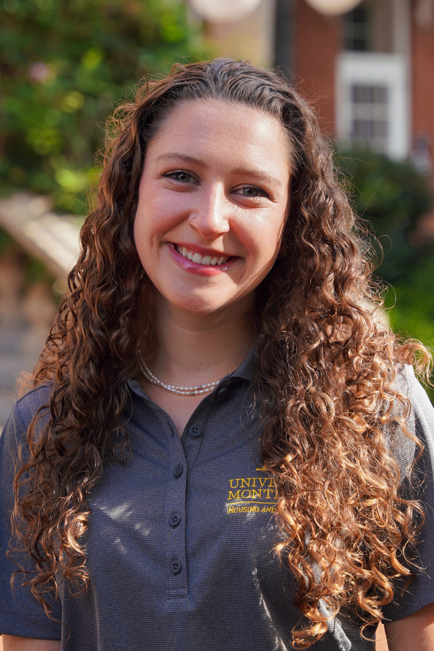 Headshot of Karle Chamberlin - female in grey shirt with long, curly brown hair